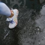 a person wearing a white shoes while stepping on wet road